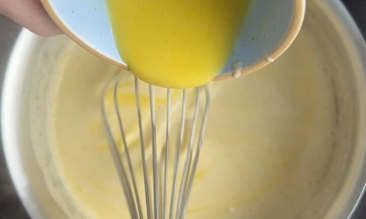 Pouring the tempered egg yolks into the eggnog mixture.