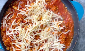 Shredded mozzarella on the top of the ingredients in the skillet.