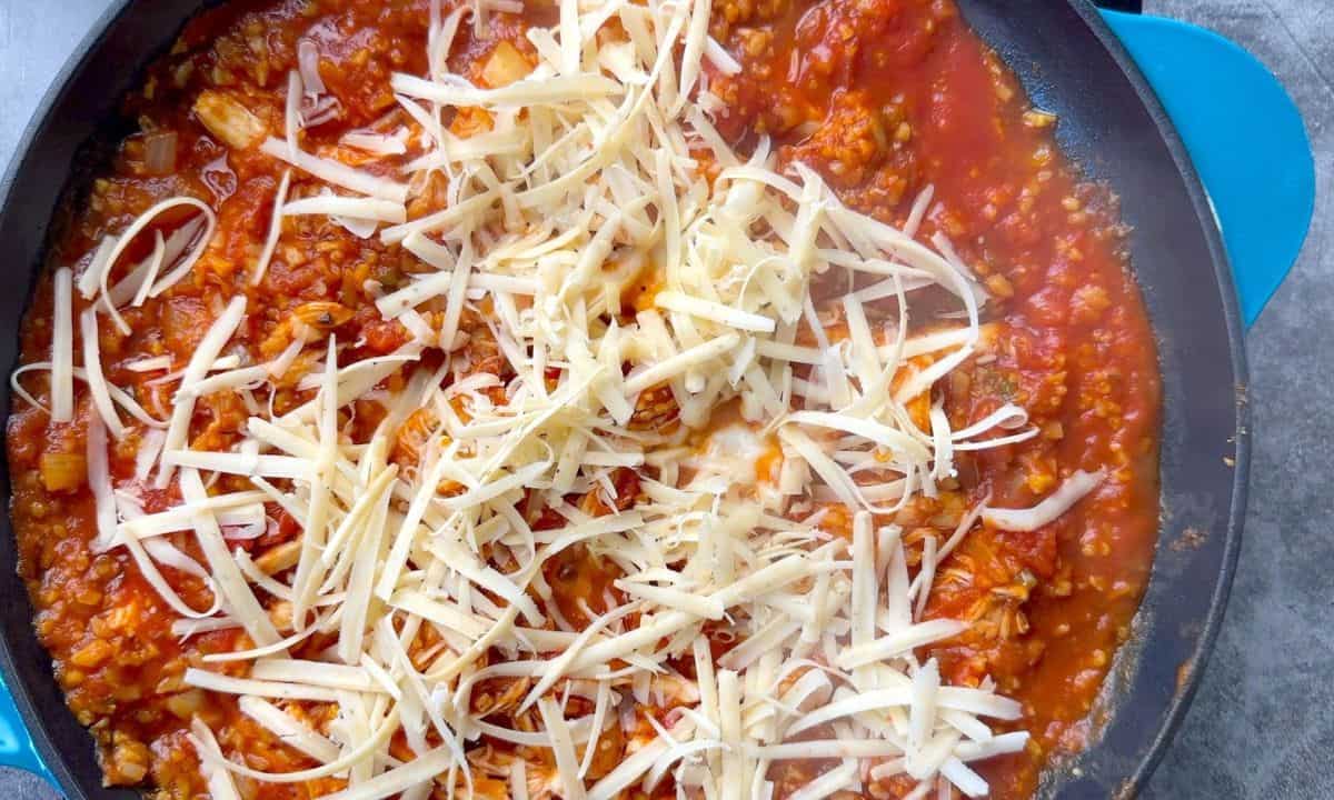 Shredded mozzarella on the top of the ingredients in the skillet.