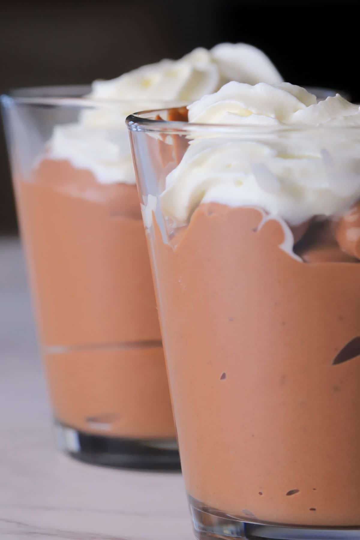 Protein mousse in glass containers topped with whipped cream.