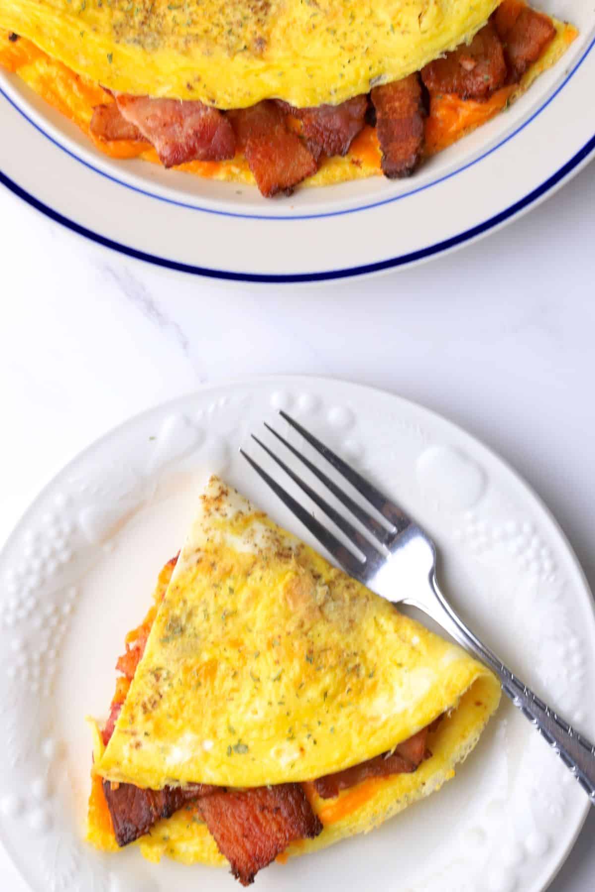 Omelet stuffed with bacon and cheddar on a plate.