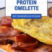 Omelet stuffed with bacon and cheddar on a plate with breakfast sausage patties.