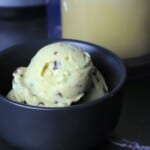Black bowl with scoops of sugar free mint chocolate chip ice cream with the ninja creami pint in the background.