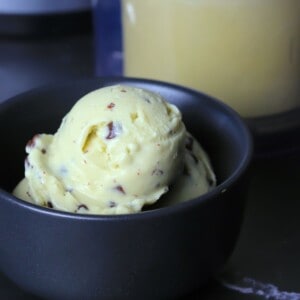 Black bowl with scoops of sugar free mint chocolate chip ice cream with the ninja creami pint in the background.