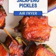 A plate with bacon wrapped pickles next to a side of ketchup.