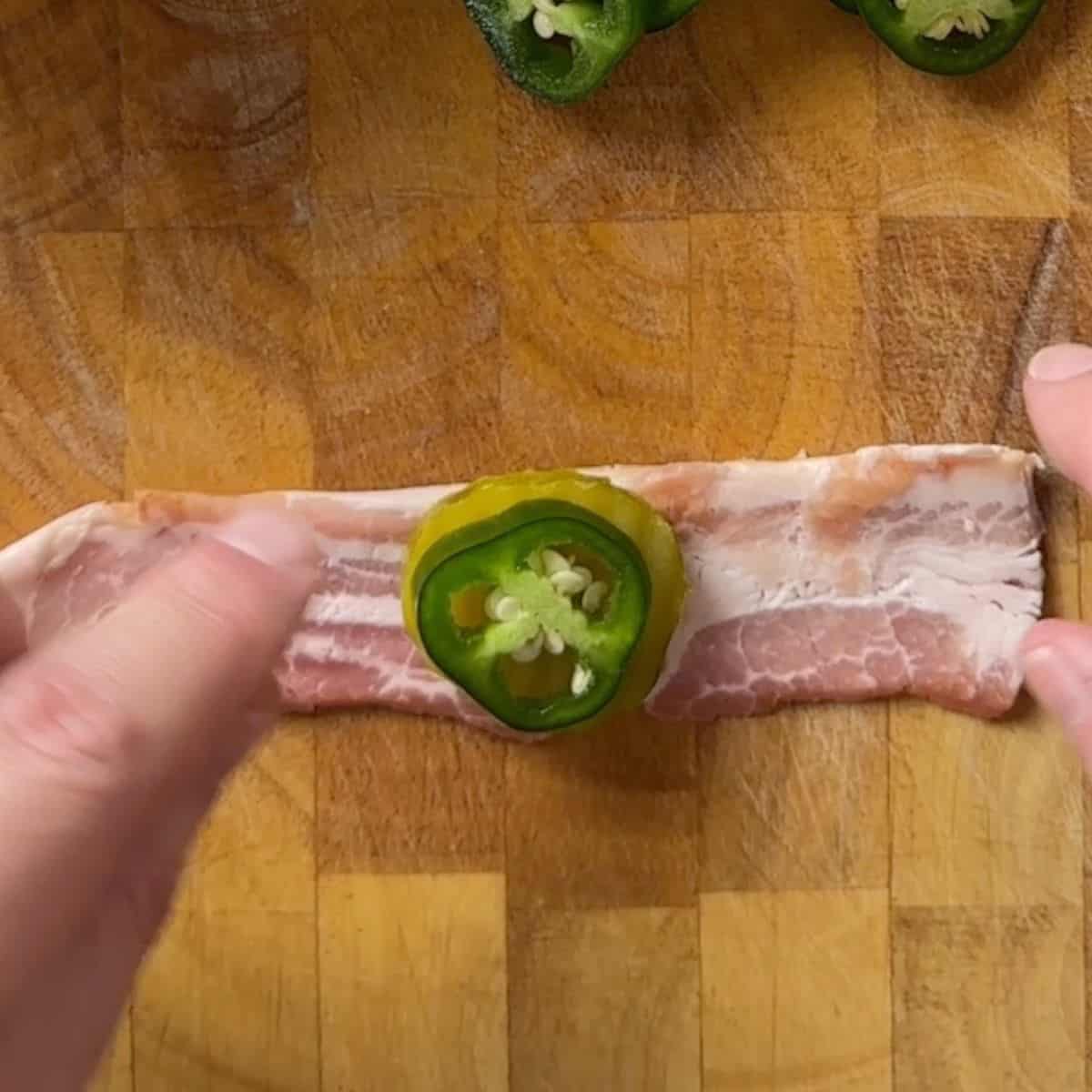 Making the bacon wrapped jalapeno pickles on the cutting board.