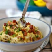 Bowl full of dairy free spaghetti carbonara topped with chopped parsley and pancetta.