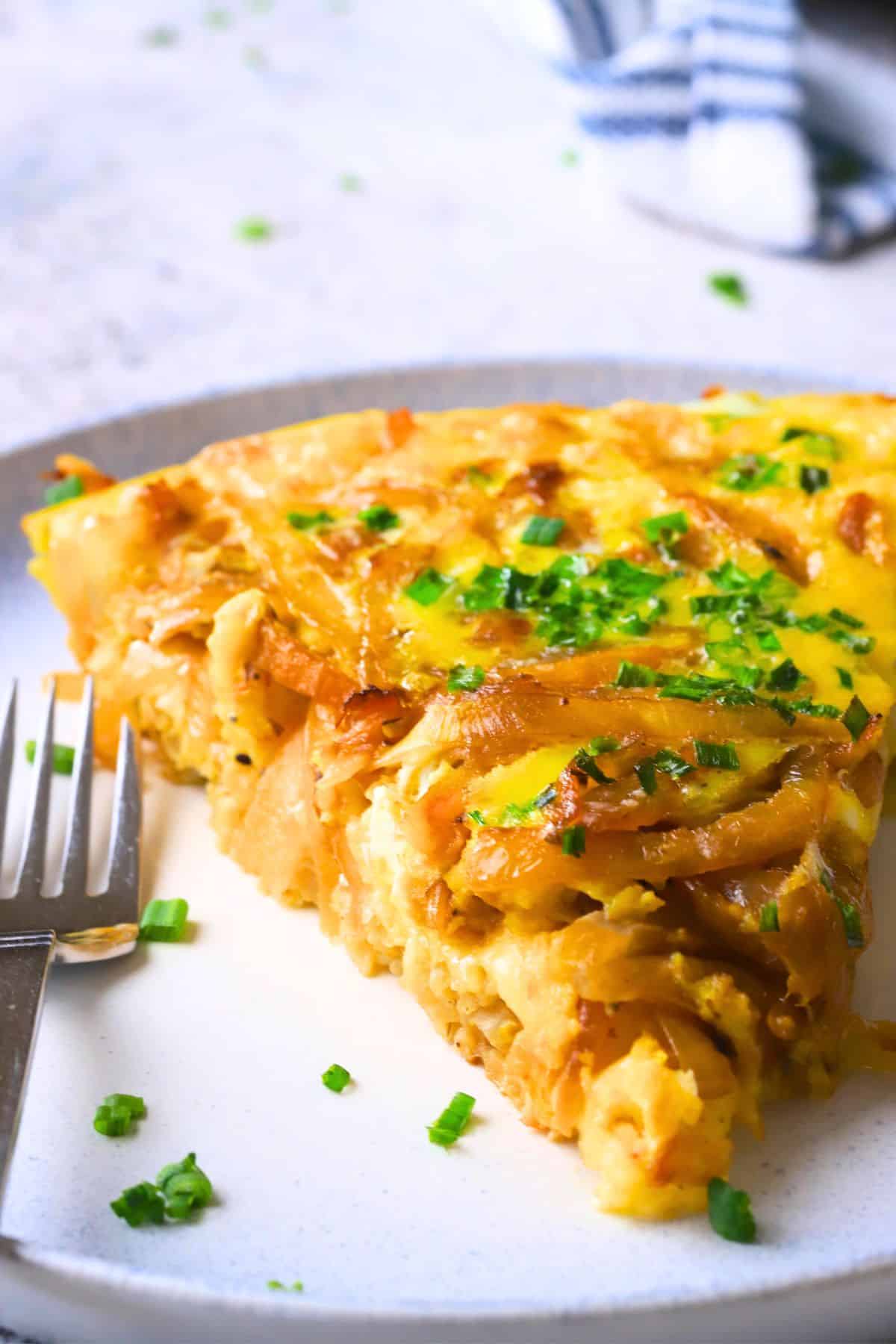 A slice of low carb french onion frittata on a plate with a fork.