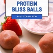 Strawberry protein bliss balls on a plate with a side of strawberry cream dip and fresh strawberries.