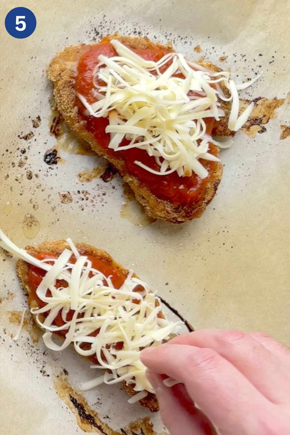 Adding shredded cheese on top of the chicken breast.