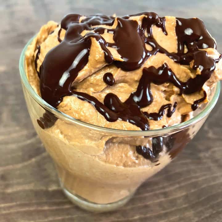 Keto peanut butter parfait drizzled with chocolate in a small glass.