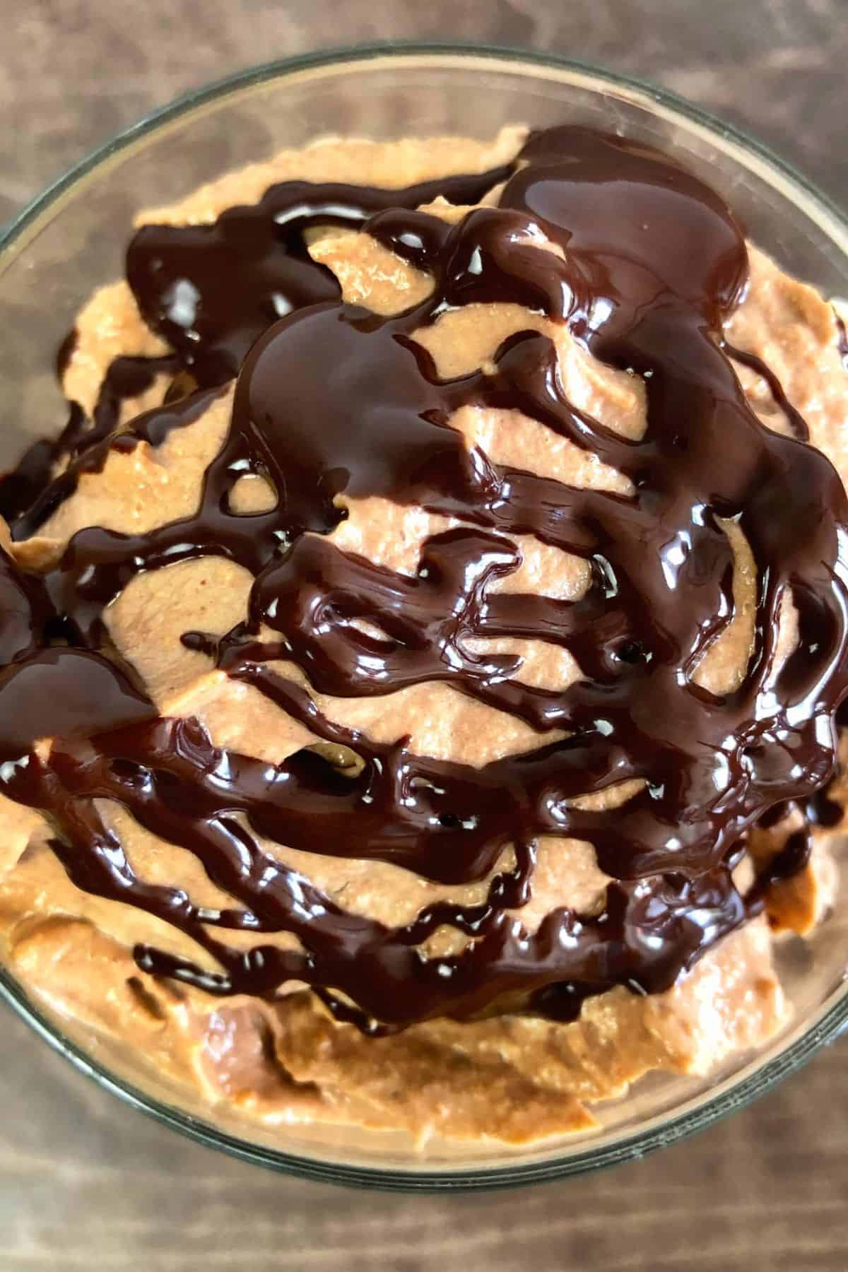 Keto peanut butter parfait drizzled with chocolate in a small glass.