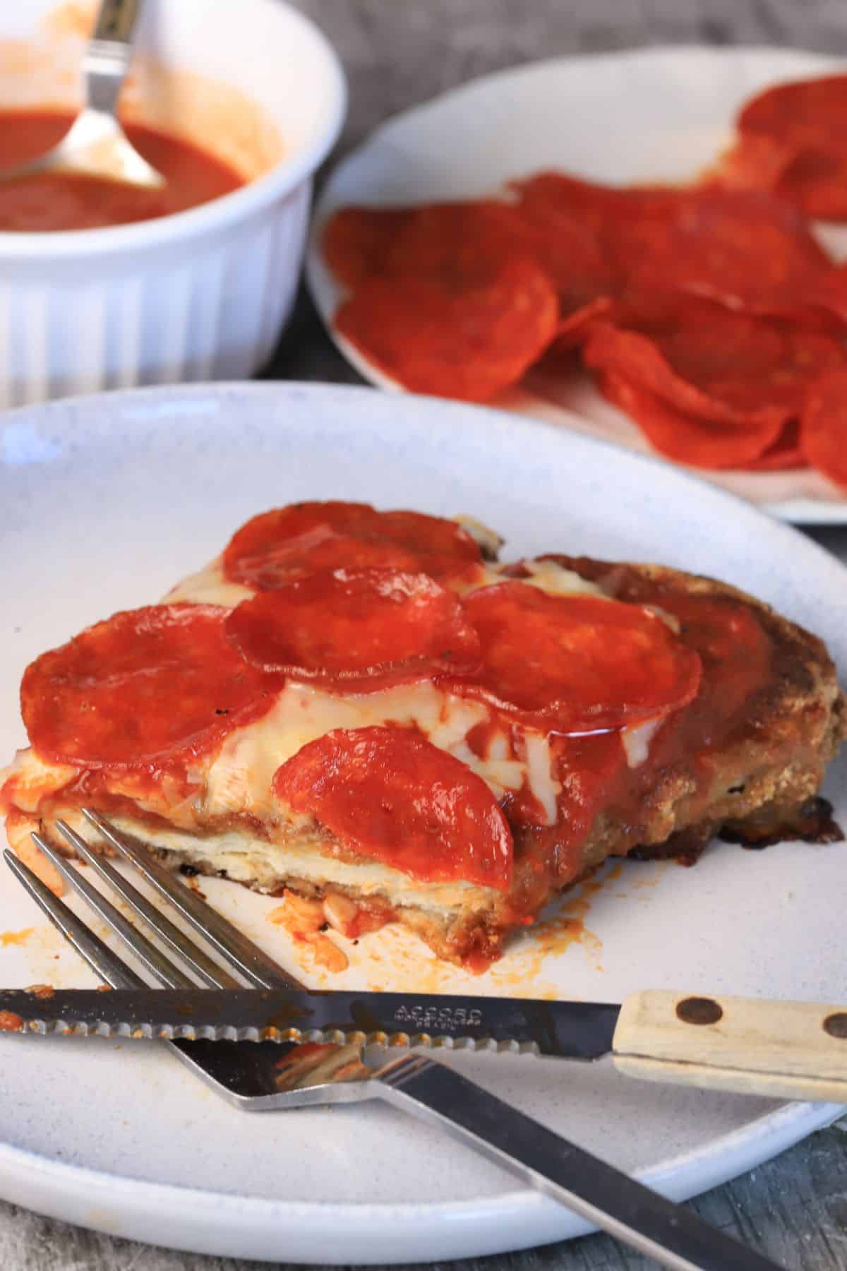 A chizza on a plate with a fork and knife.