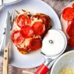 A chizza on a plate with a fork and knife.