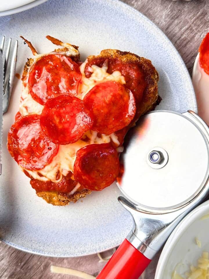 A chizza on a plate with a fork and knife.