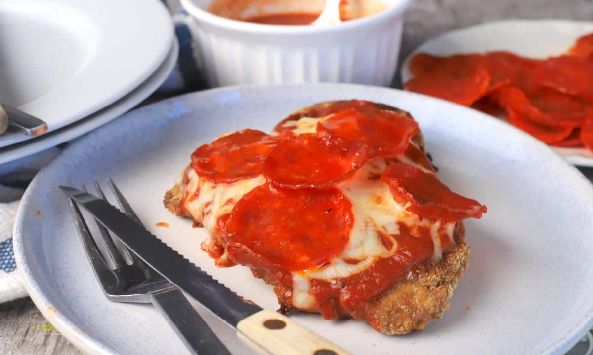 A chizza on a plate with a fork and knife.