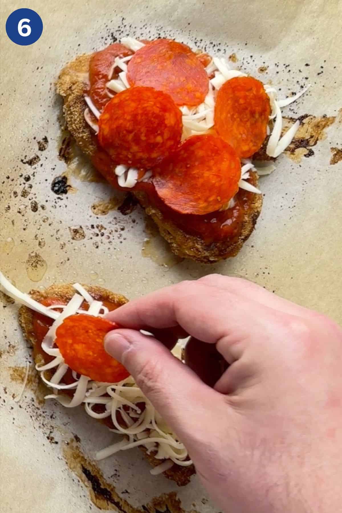 Adding pepperoni on top of the chicken breast with sauce and shredded cheese.