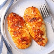 Two cooked low carb carnivore chicken breast on a plate with a fork and knife.