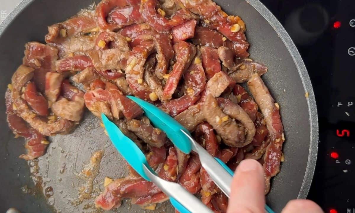 Browning the strips of beef in a frying pan.