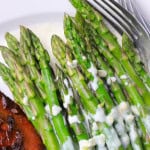 Asparagus with a cream sauce on a plate with chicken.