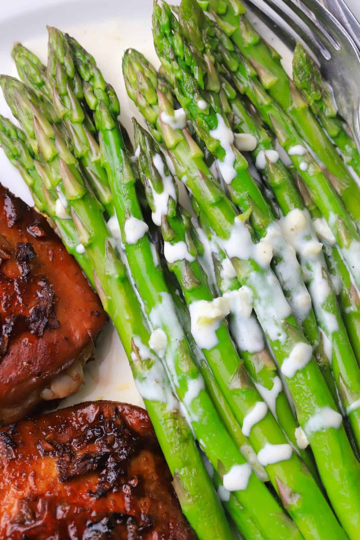 Asparagus with a cream sauce on a plate with chicken.