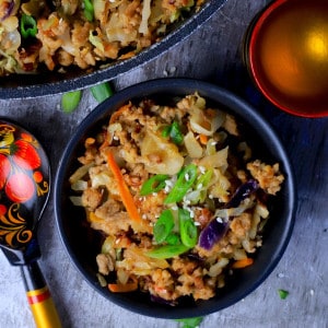 Low carb thai eggroll in a bowl in a large bowl next to a spoon, a cup and a pan with the same.