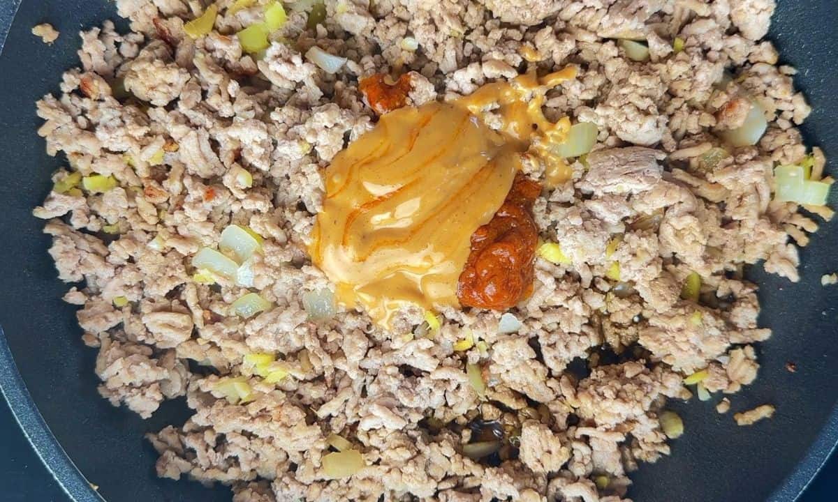 Pork mixture in the frying pan with sauce in the centre.