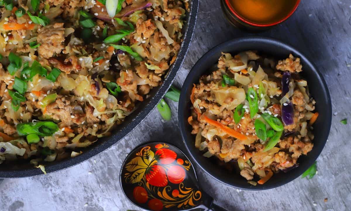 Low carb thai eggroll in a bowl in a large bowl next to a spoon, a cup and a pan with the same.