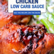 Two sticky chicken thighs with a low carb sauce on a plate next to asparagus spears.
