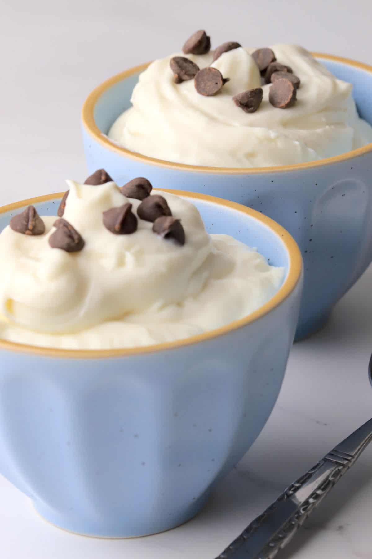 White chocolate mousse in blue bowls topped with sugar free chocolate chips.