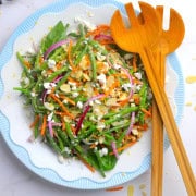 Low carb green bean salad on a plate with wooden tongs.