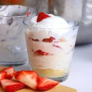 No bake low carb strawberry cup next to a wooden cutting board with sliced strawberries.