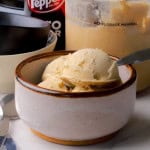 Sugar free dr pepper ice cream in a small bowl with a spoon and the can of dr pepper and the ninja creami pint in the background.