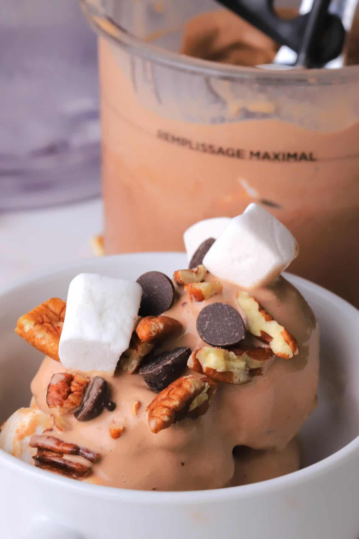 Sugar free rocky road ice cream in a bowl next to the ninja creami pint.