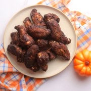 Low Carb Sweet and Savory Chicken Wings on a plate next to a small pumpkin.
