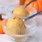 Sugar-Free Pumpkin Spice Chai Ice Cream in two bowls with spoons next to a small pumpkin ornament.