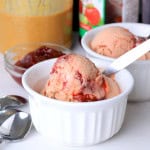 Two bowls of the low carb peanut butter and jam ice cream next to a small bowl of jam with a jar of peanut butter and jam in the background.