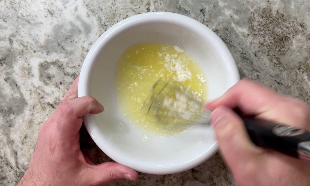 Whisking the lemon sauce in a white bowl.