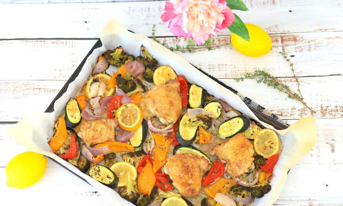 Low Carb Chicken and Veggies on a sheet pan with lemons and rosemary surrounding.