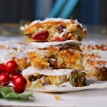 Three low carb cranberry coconut squares stacked on top of each other next to more squares and a cranberry decor.