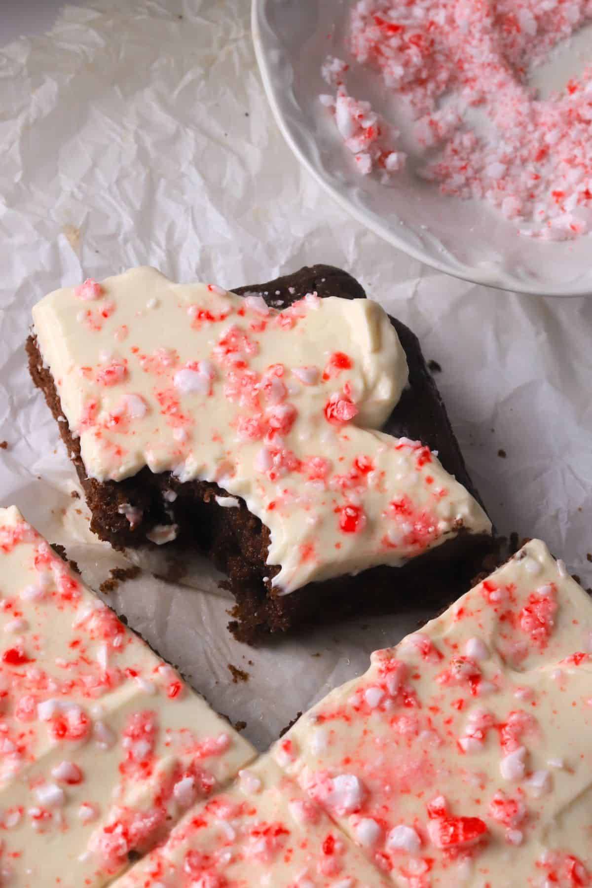 Low carb candy cane chocolate cake squares on a parchment paper, with one bite taked out of one of the squares.
