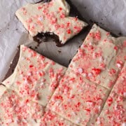 Low carb candy cane chocolate cake squares on a parchment paper, with one bite taked out of one of the squares.