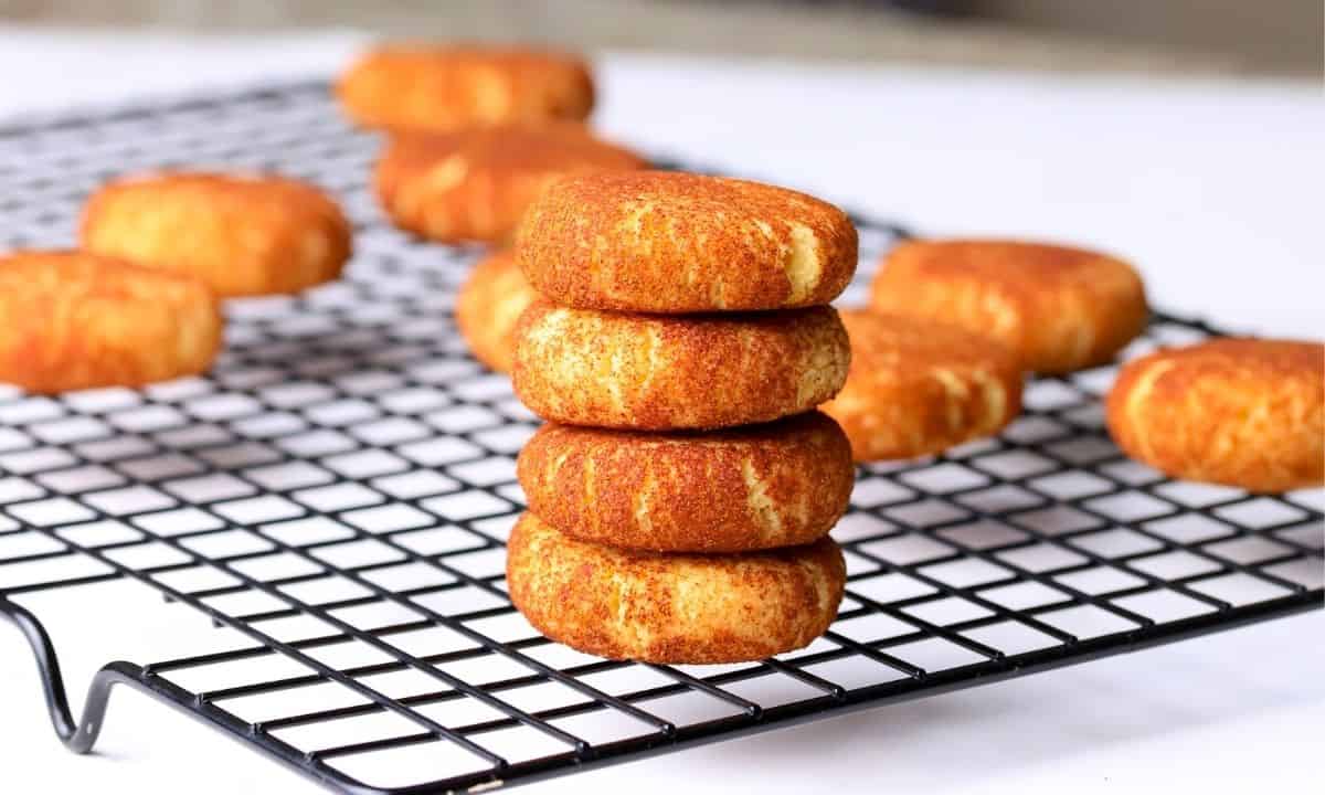 Low carb sugar free snickerdoodle cookies stacked on top of each other with other cookies in the background.