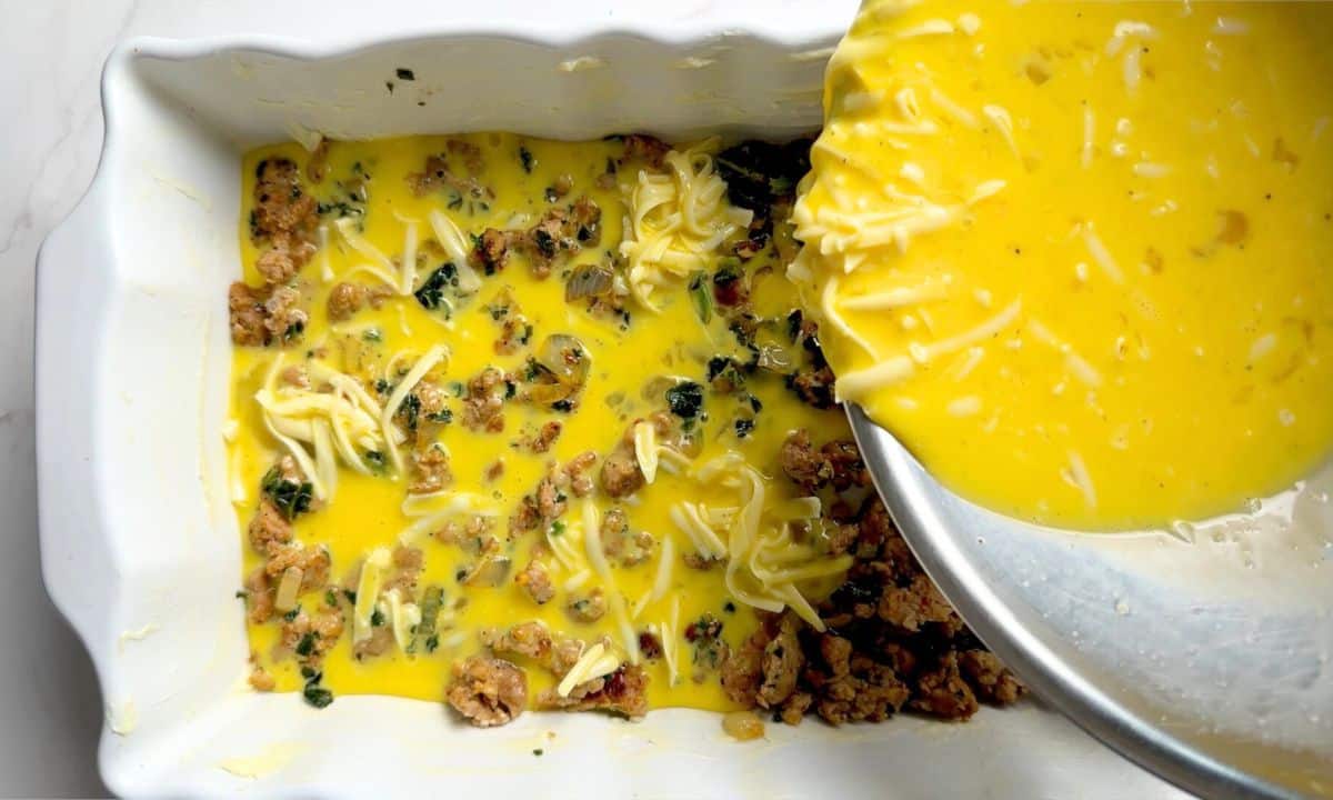 Transferring the egg mixture into the casserole dish over the sausage mixture.