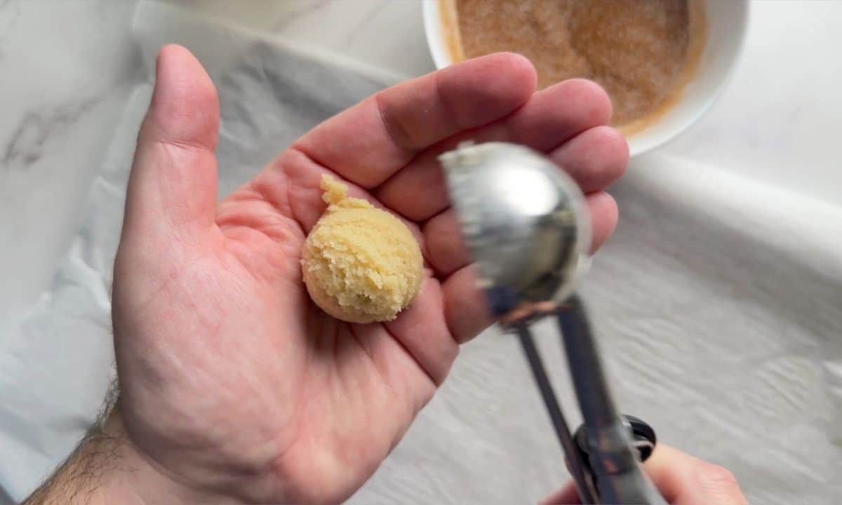 Dropping the cookie dough ball into the palm of a hand.
