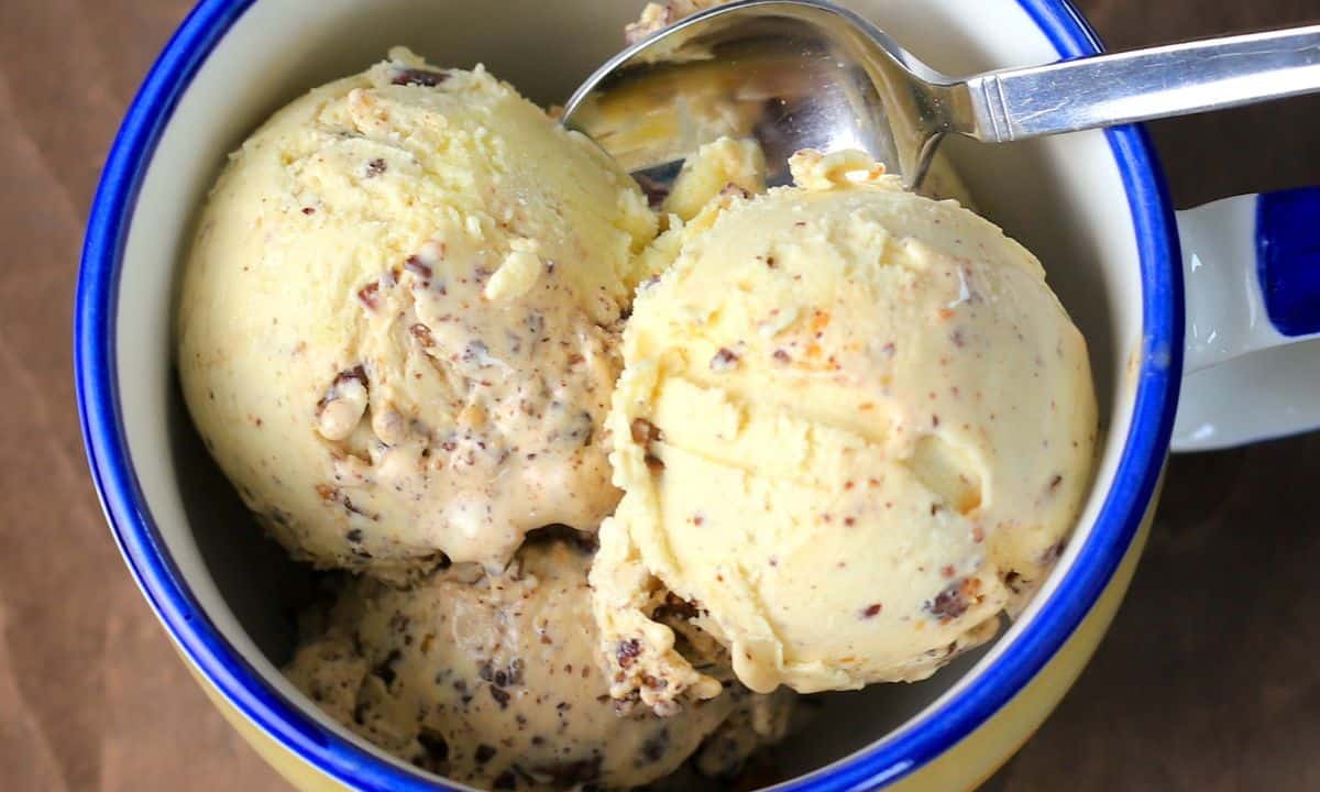 Three scoops of sugar free butter pecan ice cream in a bowl with a spoon.