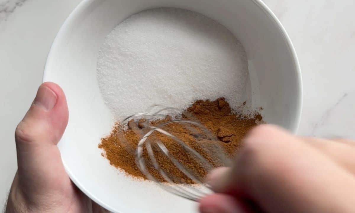 Mixing the cinnamon and sweetener together in a white bowl.