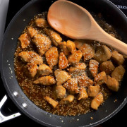 Low carb sesame chicken in the skillet with a wooden spoon.