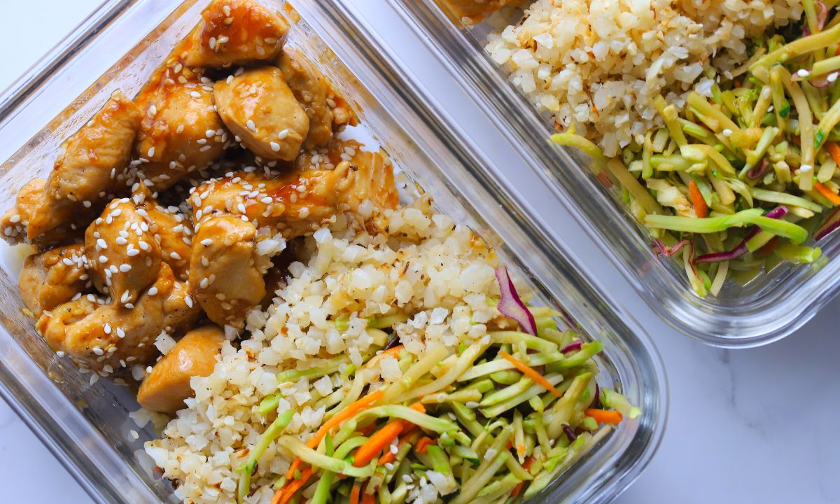 Low carb sesame chicken with cauliflower rice and asian coleslaw in glass tupperware containers.