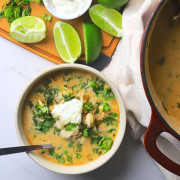 Low carb white chicken chili in a bowl next to some limes and the pot of the same.